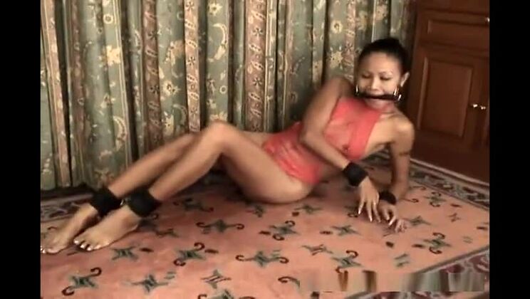 Jeune Asiatique mince en lingerie rouge, menottée et bâillonnée